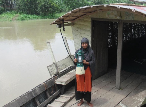 Aleya pictured holding a solar lantern on a boat school.