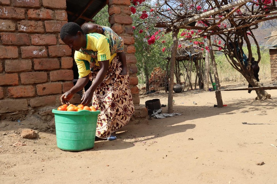 Mary Piyo pictured in her village, with a basket of fruit.