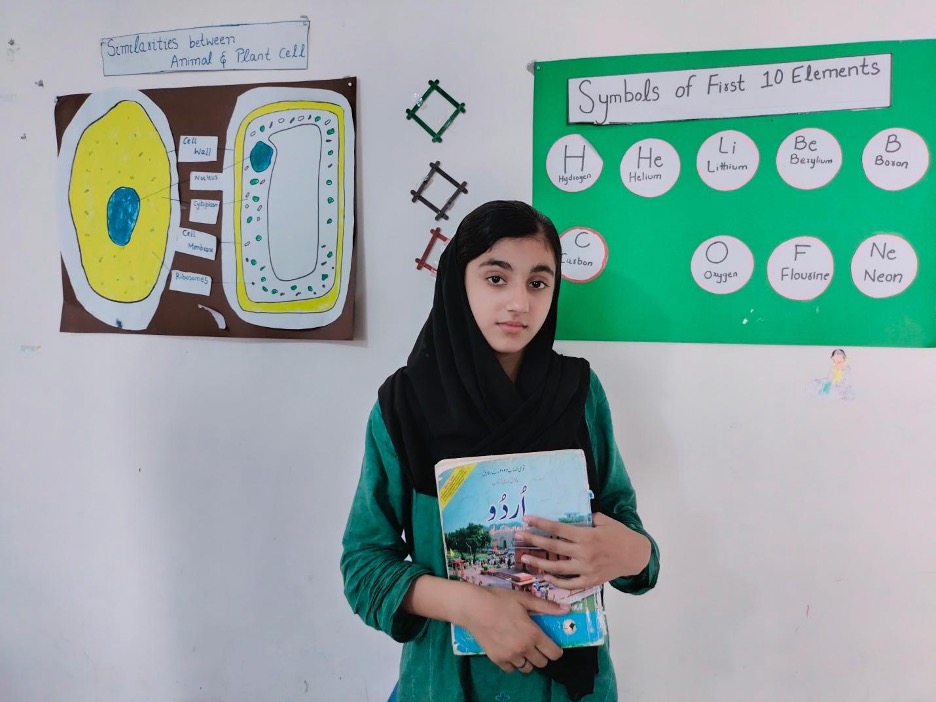 Sania in a classroom, holding a book.